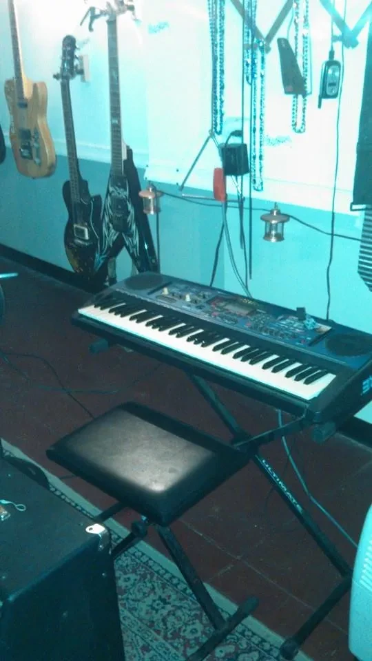 Guitars hanging on the wall above a keyboard on a stand
